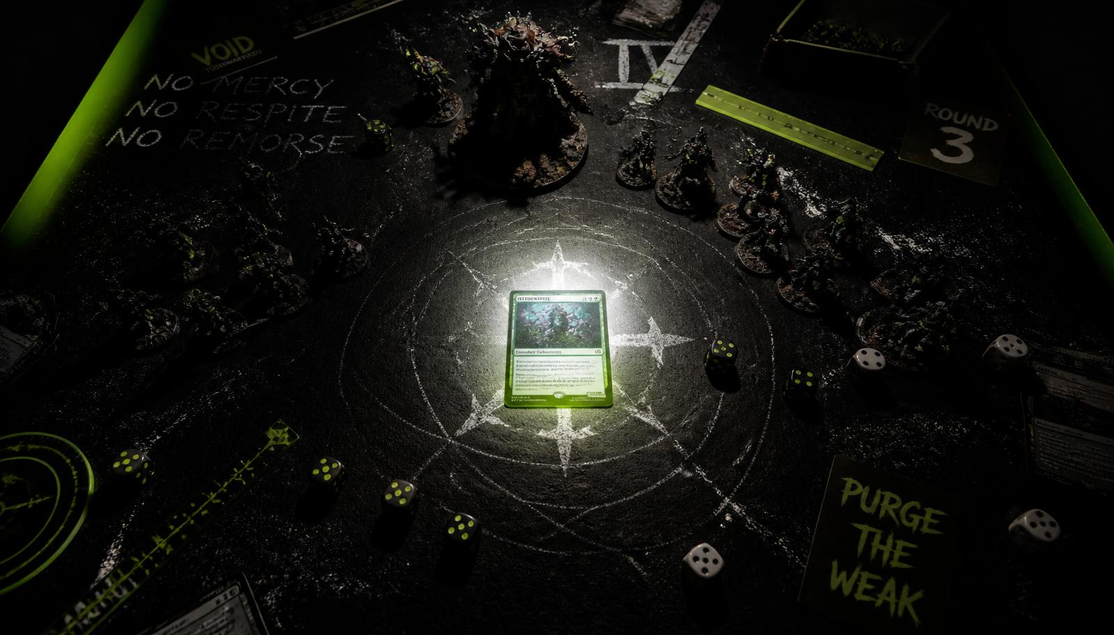 Overhead view of a black wargaming table with painted miniatures, dice and a glowing commander card under a spotlight